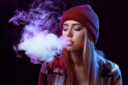 young woman smoking electronic cigarette on black background