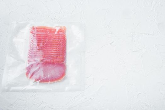 Cured pork meat or prosciutto set, vacuum packed, on white stone background, top view flat lay, with copy space for text
