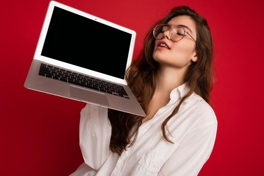 Close-up portrait of Beautiful smiling happy young woman holding computer laptop looking at netbook having fun wearing casual smart clothes isolated over wall background. free space