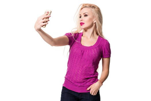 Young blonde doing selfie on isolated white background. Selfie time. Young woman in a lilac blouse