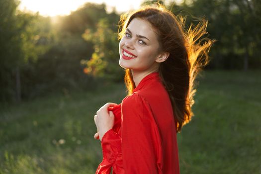 cheerful woman in a red dress in a field outdoors fresh air. High quality photo