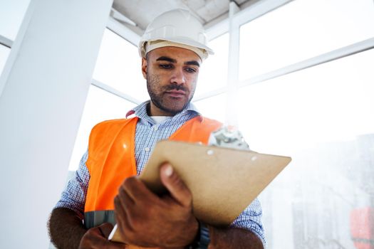 Foreman at work on construction site checking his notes on clipboard, close up
