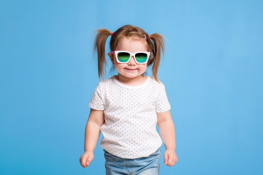 Fashion portrait of girl child on a blue background. Sunglasses.