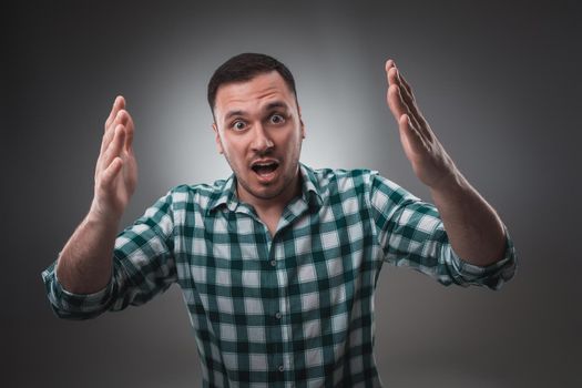 Portrait of man on gray background. Man showing different emotions. Man in green shirt in a cage