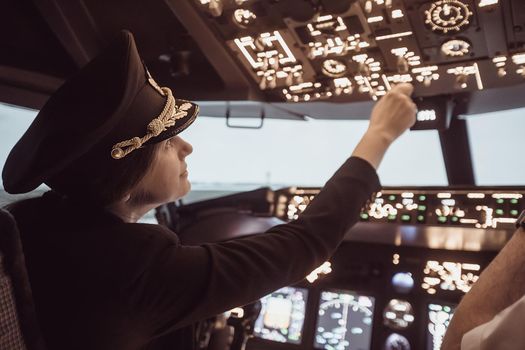 Female pilot the captain of the plane prepares for take-off in the plane cockpit. Girl pilot in uniform flying craft plane in the sky