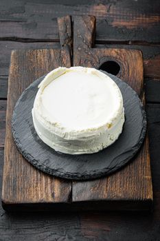 A fresh, ricotta cheese, on wooden cutting board, on old dark wooden table background
