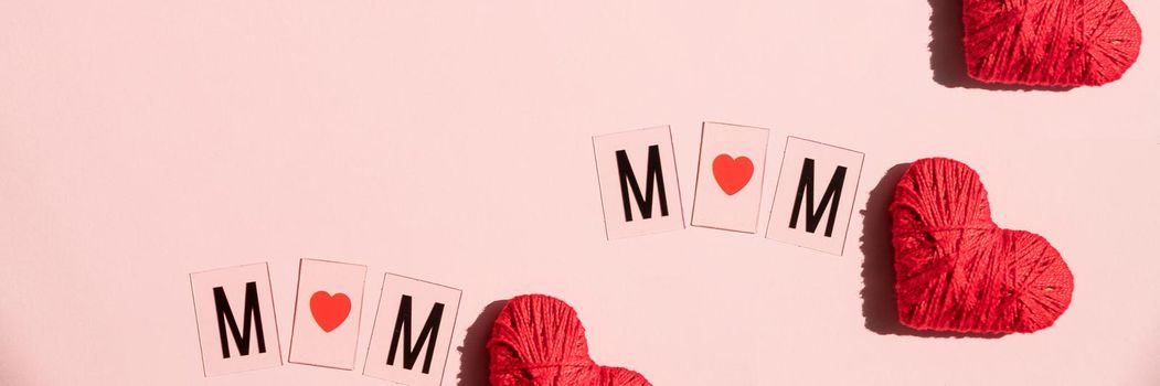 Happy mother's day greeting card, Love mom word on red fabric heart shape hanging over white background with copy space for text