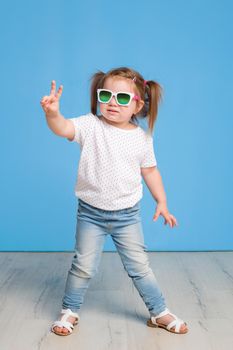 Fashion portrait of girl child on a blue background. Sunglasses.