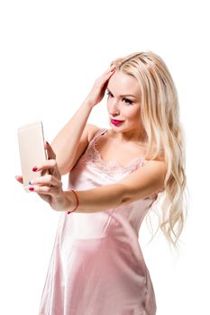 Young blonde doing selfie on isolated white background. Selfie time. Young beautiful woman in silk dress