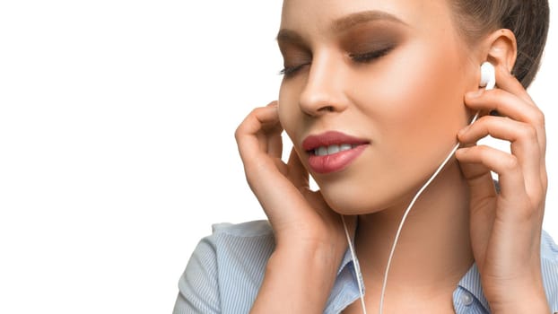 Close up portrait of a young woman listening to the music via earphones.