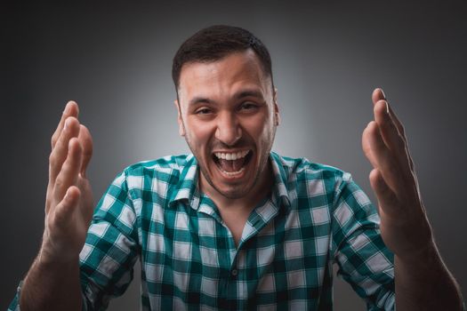 Portrait of man on gray background. Man showing different emotions. Man in green shirt in a cage