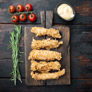 Crispy fried chicken broast cuts on old dark wooden table, top view.