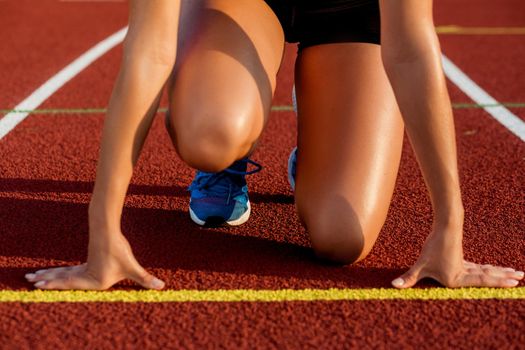 Close-up of woman's legs in blue sneakers on start before jogging. Red treadmill at the stadium