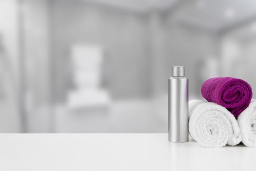 Spa still life with towels and skincare cosmetics against blurred background, close up