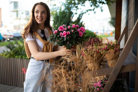 charming young woman buying flowers at garden summer shop.