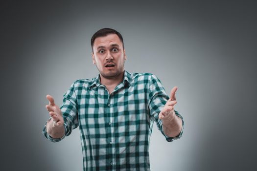 Portrait of man isolated on gray background. Man showing different emotions. Man in green shirt in a cage