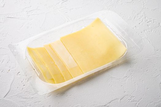 Sliced delicious edam cheese set, in plastic pack, on white stone background
