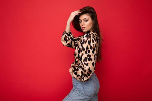 Close-up portrait of young nice-looking attractive lovely glamorous brunet woman wearing leopard blouse isolated on red color background with free space.