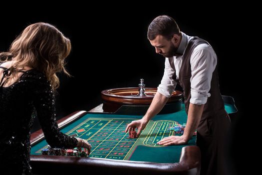 Croupier and woman player at a table in a casino. Picture of a classic casino roulette wheel. Gambling. Casino. Roulette. Poker