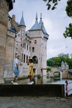 Castle de Haar Utrecht, couple men and woman mid age European and Asian visit De Haar Castle in Dutch Kasteel de Haar is located in Utrecht Netherlands during Spring with flowers in the garden