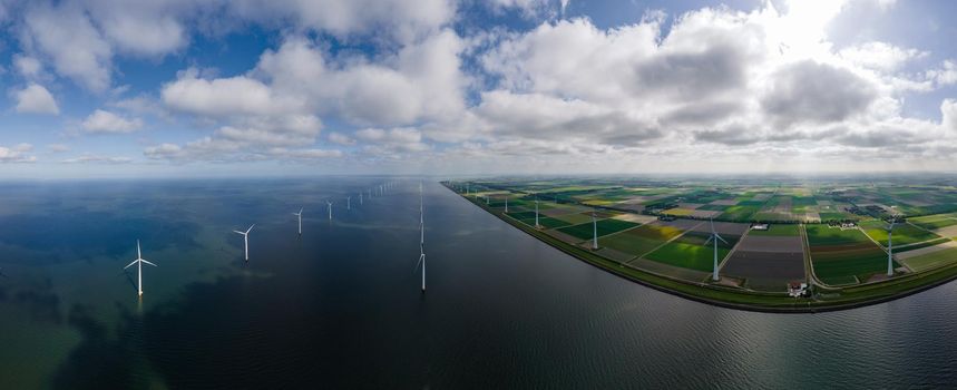 offshore windmill park with clouds and a blue sky, windmill park in the ocean aerial view with wind turbine Flevoland Netherlands Ijsselmeer. Green energy 