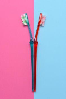 Two toothbrushes on a pink and blue background. Flay lay high angle view with copy space.