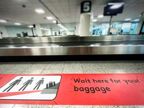 A red patch on the floor indicating where to wait for baggage claim at an airport. Icons and pictogram. Arrival at the airport