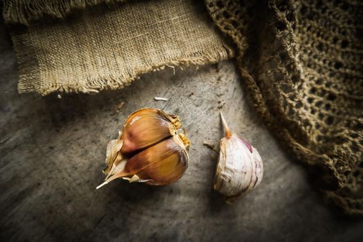 Garlic cloves and natural linen napkin on rustic wooden background