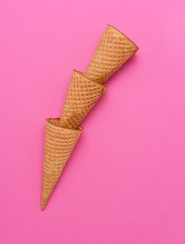 Three nested ice cream cones on a pink background. Flat lay minimalist styling. 