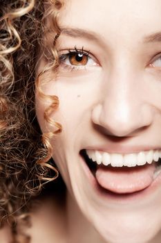 Beautiful brunette girl with long curly hair. Closeup studio portrait. Happy face expression. Tongue out.