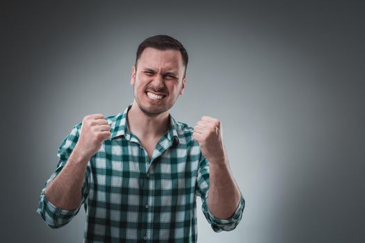 Portrait of man isolated on gray background. Man showing different emotions. Man in green shirt in a cage