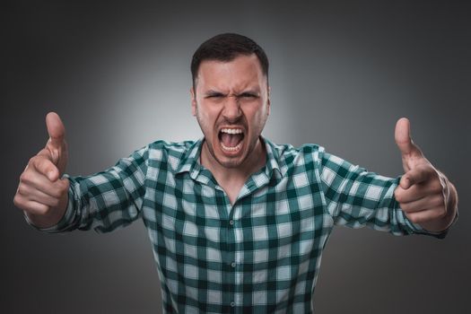 Portrait of man on gray background. Man showing different emotions. Man in green shirt in a cage