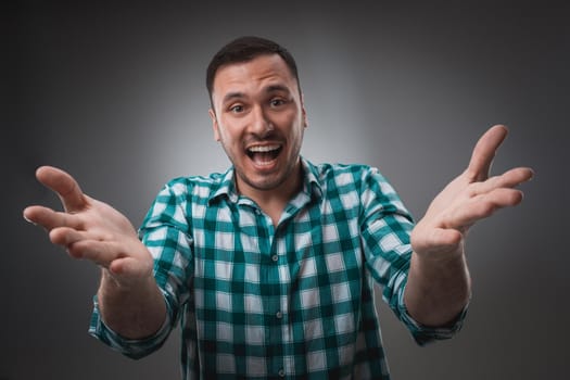 Young man and sign of victory isolated on gray background. Emotion concept