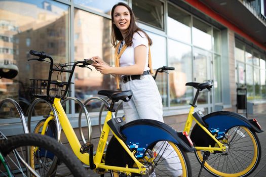 a young woman checks in a bike rental app in the city.