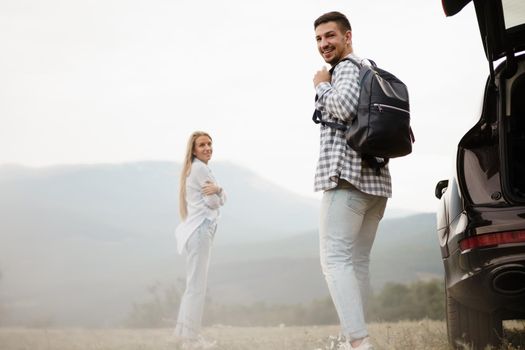 Young couple on road trip relaxing and enjoying the view of mountains