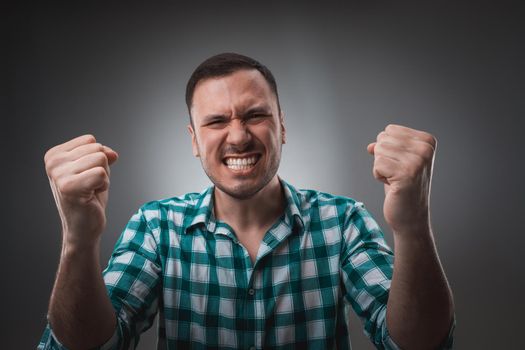 Portrait of man isolated on gray background. Man showing different emotions. Man in green shirt in a cage