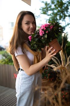 cute young woman holding her favorite flowers in a street garden shop.