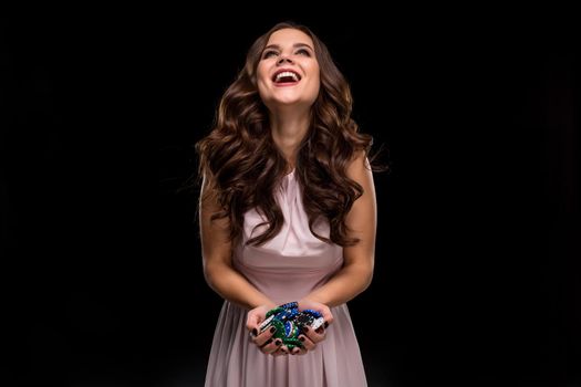 Female Poker player with paint black nails hold her poker chips to make a bet. Gambling and casino business concept. Studio shot on a black background. Casino