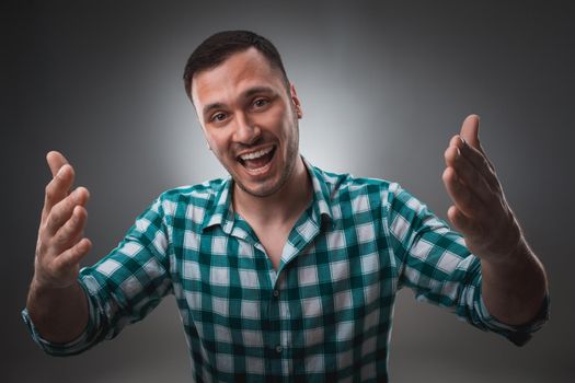 Portrait of excited man looking at the camera and points at you with a finger. Isolated on gray background. Emotion concept