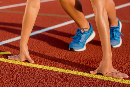 Close-up of woman's legs in blue sneakers on start before jogging. Red treadmill at the stadium