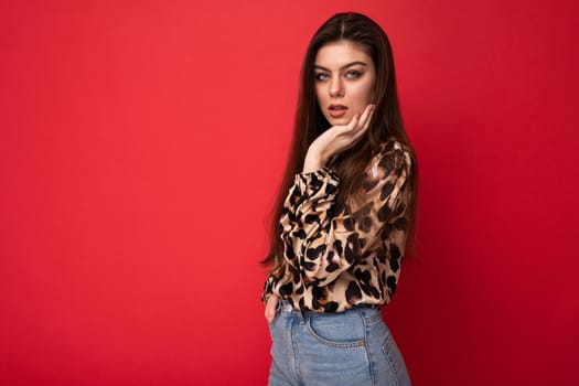 Close-up portrait of young nice-looking attractive lovely glamorous brunet woman wearing leopard blouse isolated on red color background with free space.