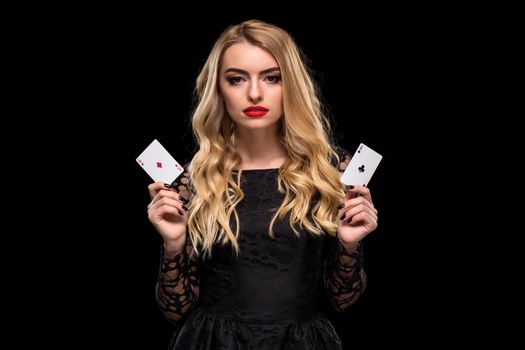 Beautiful young woman in black dress holding two ace of cards in her hand, isolated on black background. Poker. Casino. Roulette Blackjack Spin. Caucasian woman looking at camera