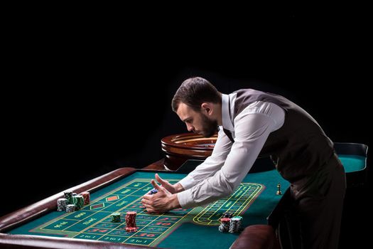 Croupier behind gambling table in a casino on a black background. Gambling. Casino. Roulette. Poker