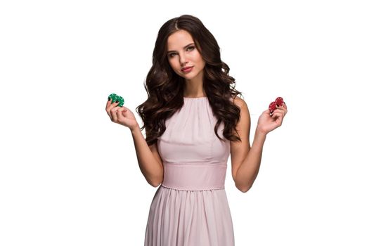 Sexy woman in a chic gently pink dress holding colored poker chips. Isolated on white background. Woman winning. Casino. Poker. Victory. Luck Roulette Blackjack Spin. Big win emotions