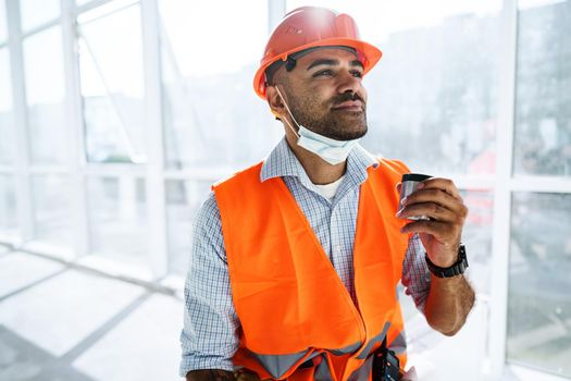 Portrait of a man worker in workwear on a break drink coffee and have rest, close up