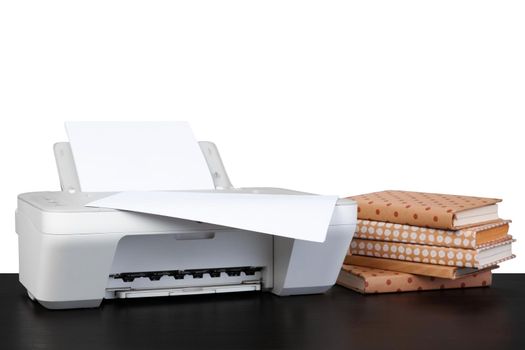 Printer and stack of books on black table against white background, close up