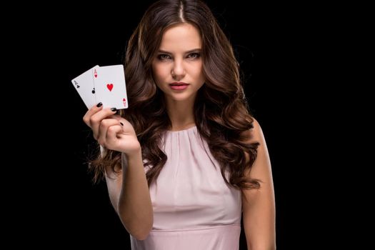 Attractive young woman in a sexy light dress holding the winning combination of poker cards. Two Aces. Studio shot on a black background. Casino