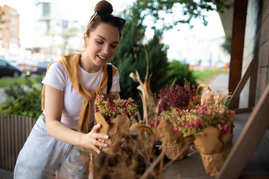 happy caucasian young woman chooses potted flowers to buy at outdoor garden stall.