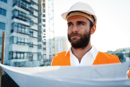 Builder or architect in hardhat supervising a project, looking at blueprints, close up