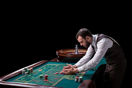 Croupier behind gambling table in a casino on a black background. Gambling. Casino. Roulette. Poker